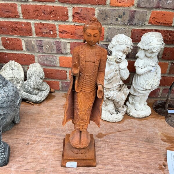 Detailed metal Buddha garden ornament standing in a garden setting.