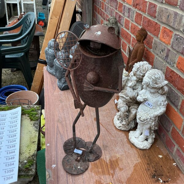 Whimsical metal frog garden ornament for outdoor decoration.