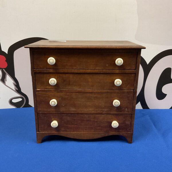 Front view of vintage miniature chest of drawers with bone knobs.