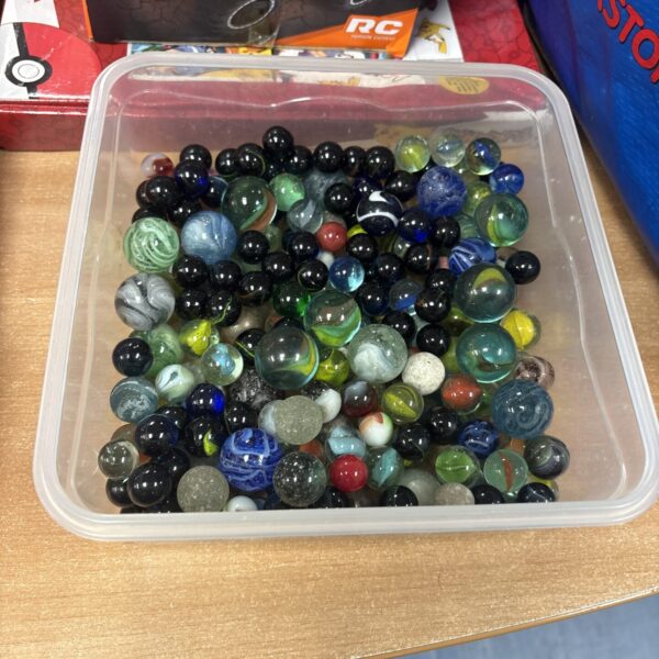 Colourful mixed marbles in a plastic container, vintage toy collection.