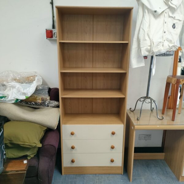 Tall modern wooden bookcase with drawers for home storage.