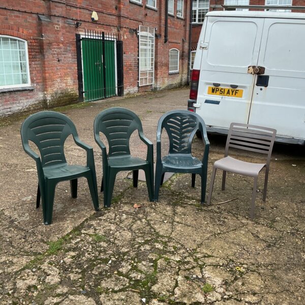 Set of four plastic garden chairs in a garden setting.
