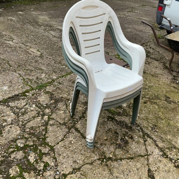 Stack of four plastic garden chairs for outdoor use.
