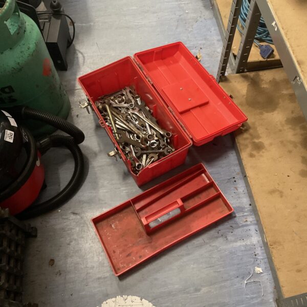 Red plastic toolbox filled with spanners and hand tools.