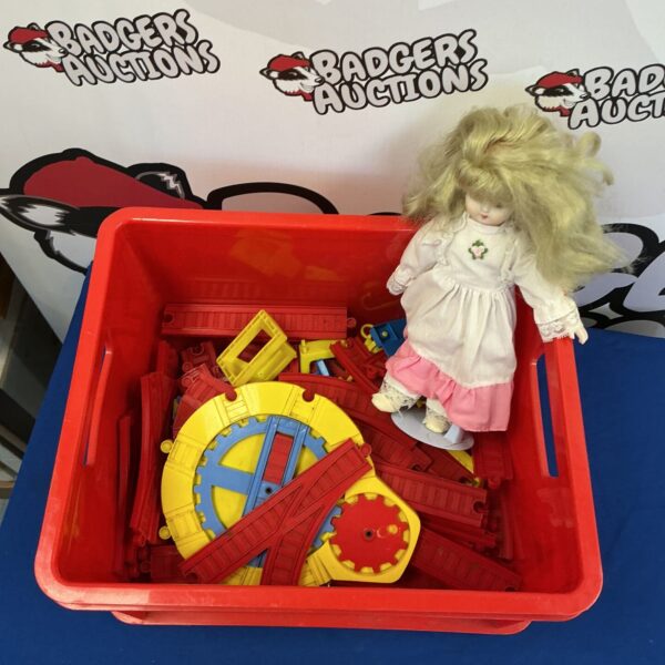 Colourful plastic train track and vintage doll set for collectors.