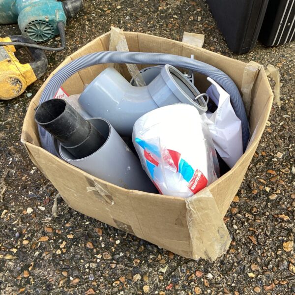 Assorted plumbers tubing and piping in a cardboard box.