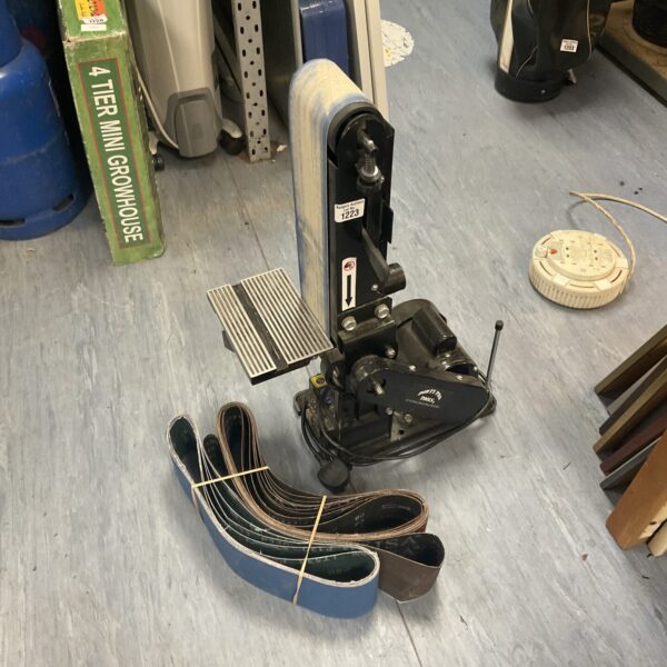 Dirty pro belt sander with spare sanding belts for workshop use.