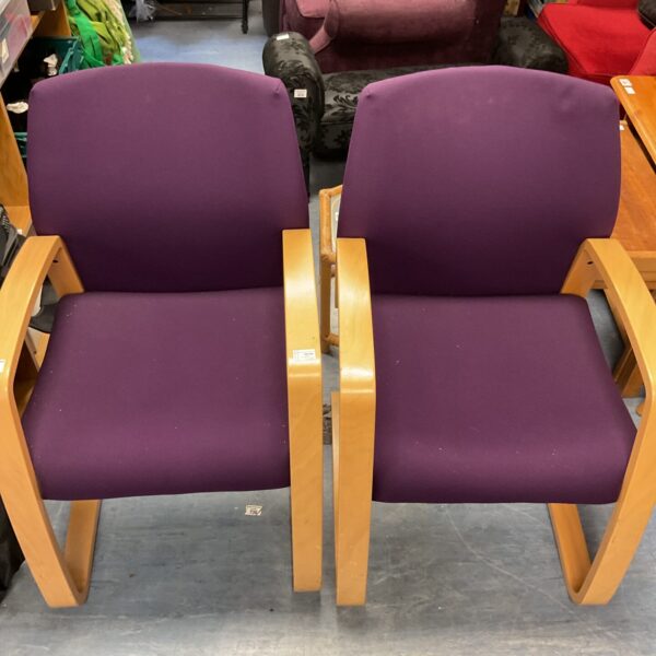 Two purple open armchairs with wooden frames.