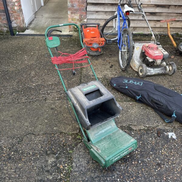 Vintage Qualcast 30 electric lawn raker in a garden setting.