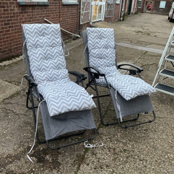Pair of reclining garden chairs with cushions in a garden setting.