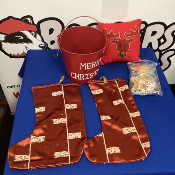 Red Christmas bucket filled with holiday contents and festive gifts.