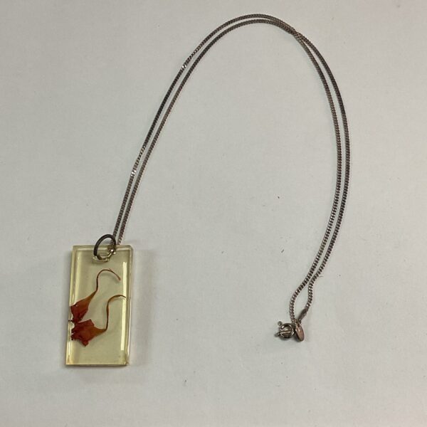 Silver chain necklace with a clear resin floral pendant.