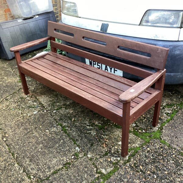 Weathered rustic wooden garden bench in a garden setting.