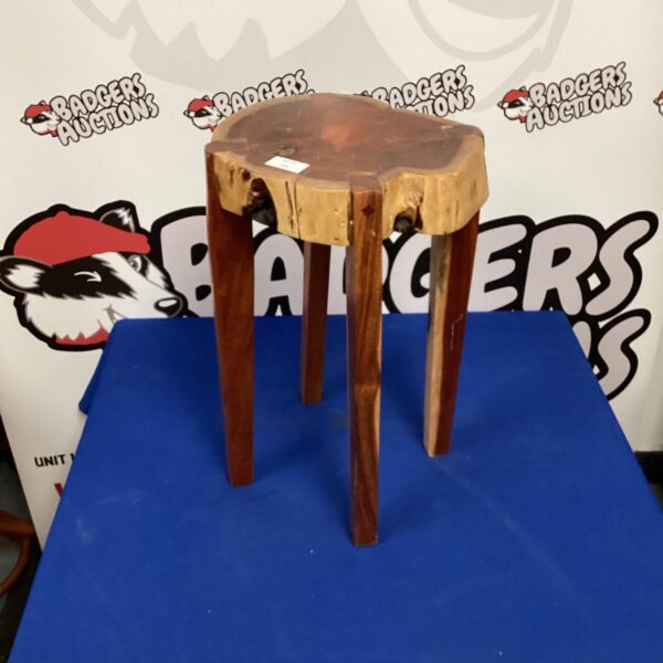 Rustic wooden stool with a circular seat and four legs.