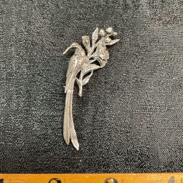 Vintage silver bird of paradise brooch with intricate floral details.