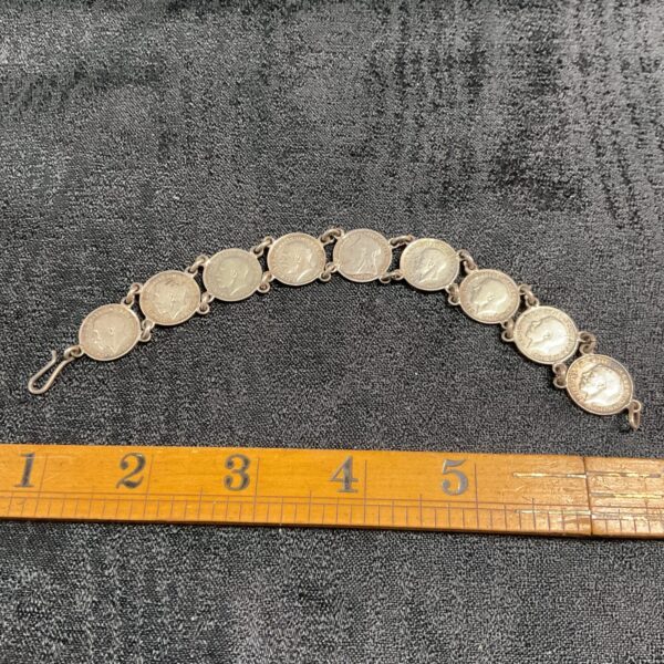 Vintage silver coin bracelet displayed on a dark surface.
