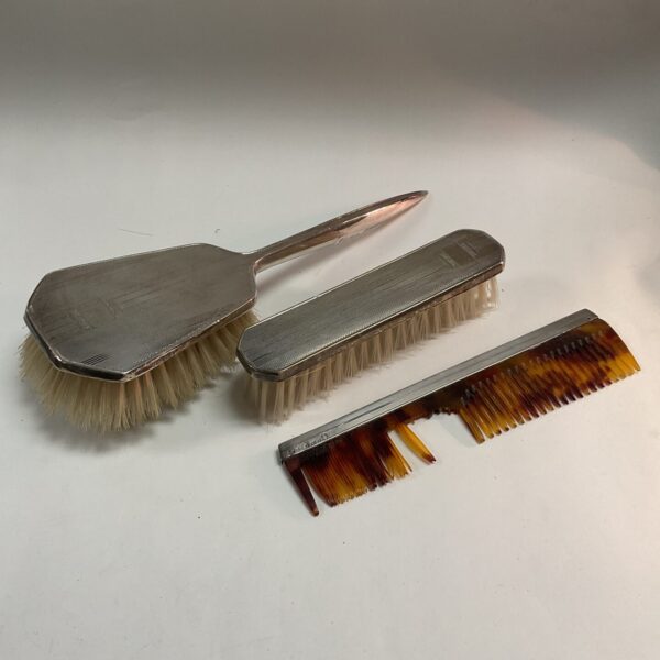 Antique silver dressing table brush set on a neutral background.