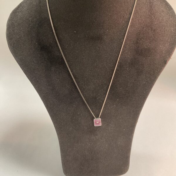 Silver enamel pendant necklace displayed on a mannequin.