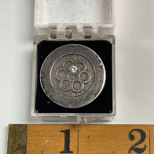 Hallmarked silver brooch with floral design and white stone.