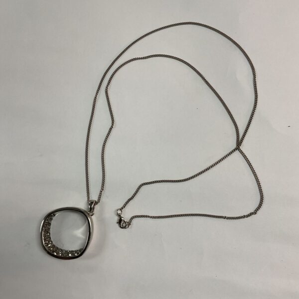 Silver tone necklace with large hoop pendant and clear stones.