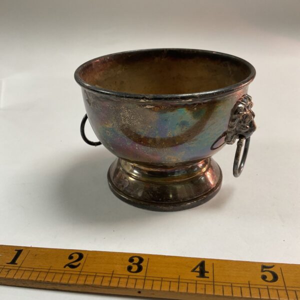 Antique silver bowl with lion head handle, detailed view.