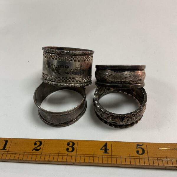 Four hallmarked silver napkin rings with floral embossed designs.