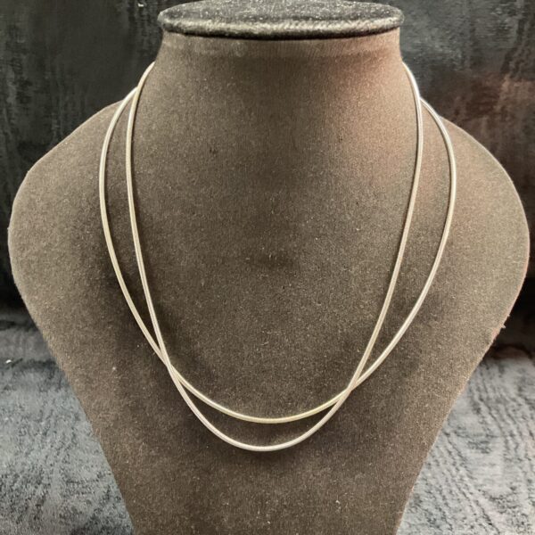 Pair of delicate silver snake chain necklaces on display.
