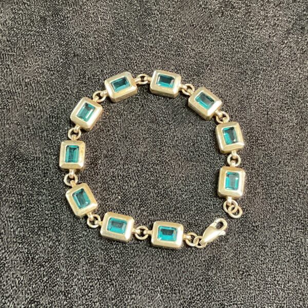 Silver and topaz bracelet with gemstone detailing.