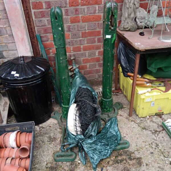 Vintage Slazenger cast iron tennis net poles in a garden setting.