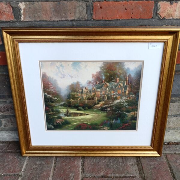 Gilt-framed Thomas Kinkade print depicting a serene garden landscape.