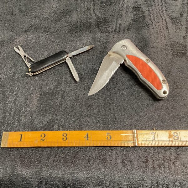 Two red-handled pocket knives with stainless steel blades.