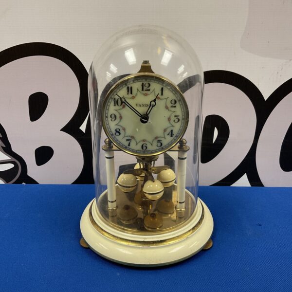 Antique Vandor torsion clock with clear dome and visible movement.