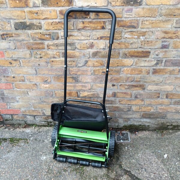 Vintage Victor push lawn mower in a garden setting.