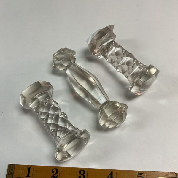 Set of three antique Victorian glass knife rests on a white surface.