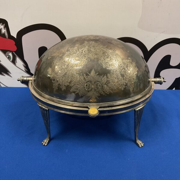 Ornate Victorian silver plate breakfast warmer on blue background.