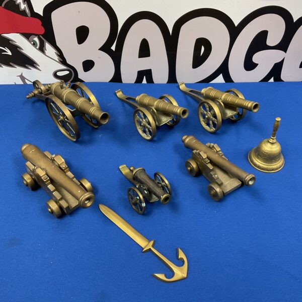 Vintage brass cannons, anchor, and bell collection for nautical decor.