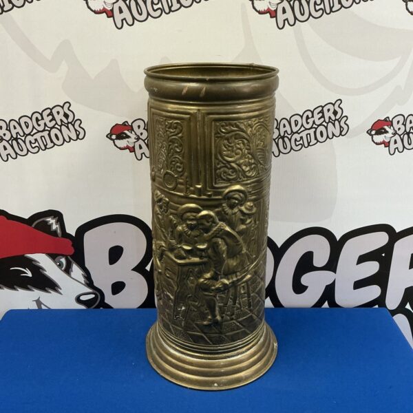 Vintage brass stick stand with detailed tavern scene embossing.