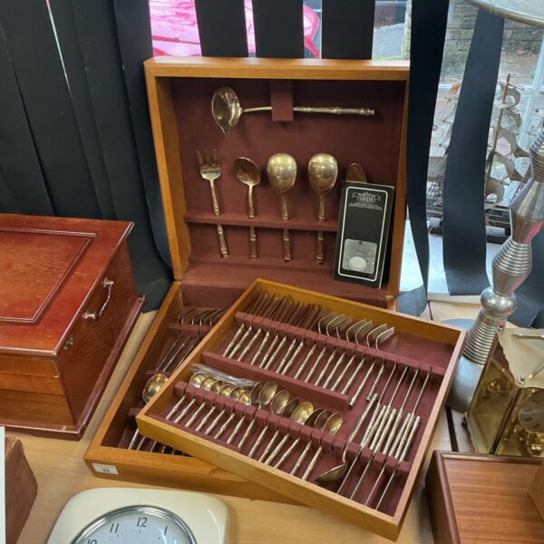 Vintage bronze cutlery set displayed in a wooden presentation box.