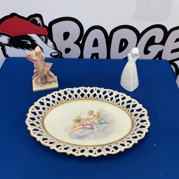 Vintage ceramic plate with cherub and floral design.