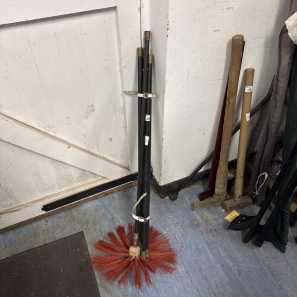 Vintage chimney sweeping brush with wooden handle and bristles.