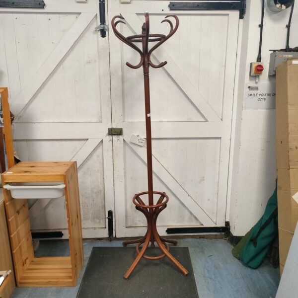 Vintage wooden coat, hat, and umbrella stand in a hallway.
