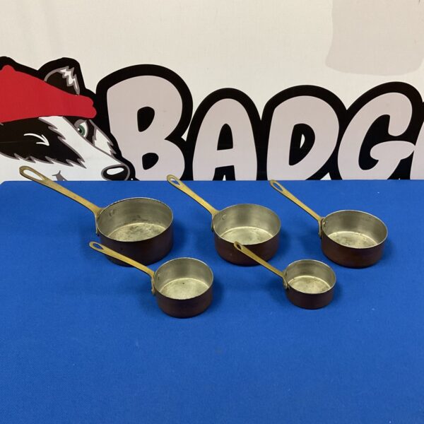 Set of five vintage graduated copper pans with brass handles.