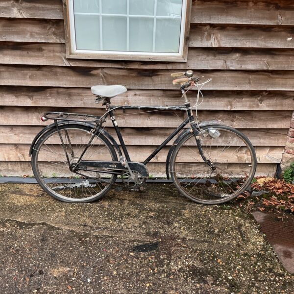 Side view of a vintage Hopper bicycle in front of a wooden wall.