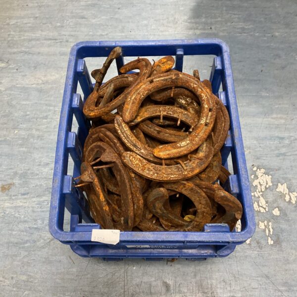Crate of vintage horseshoes with rustic patina.