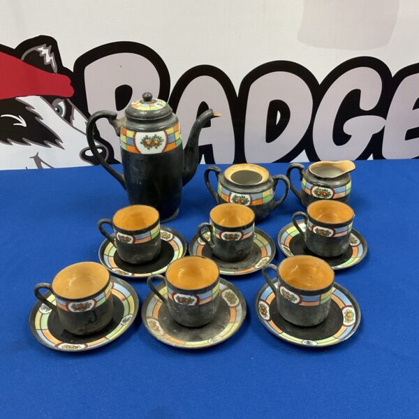 Vintage Japanese teaset with black floral pattern on display.