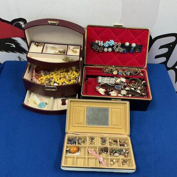 Vintage burgundy and cream jewellery boxes filled with costume jewellery.