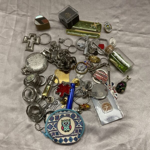 Vintage keyring and jewellery lot displayed on a tray.