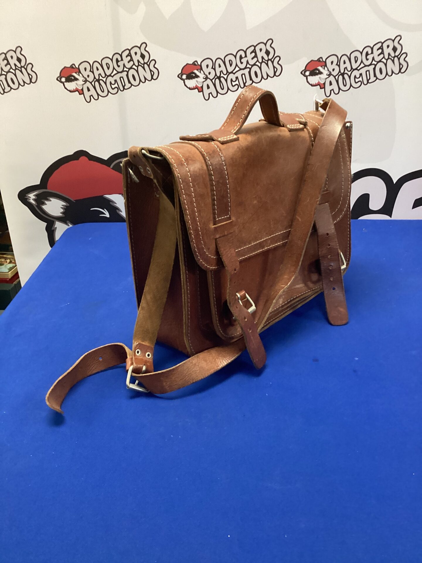 Front view of a vintage brown leather satchel with buckle closure.