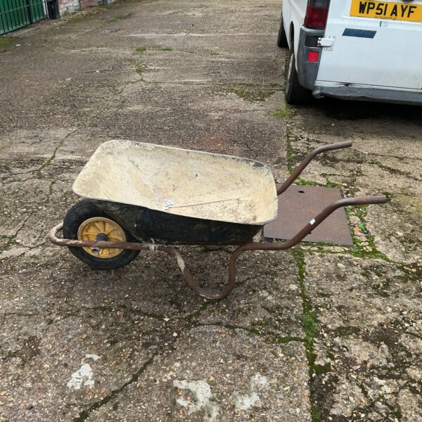 Vintage metal wheelbarrow in a garden setting.