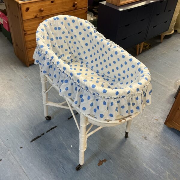 Vintage Moses basket on wheels with blue polka dot lining.